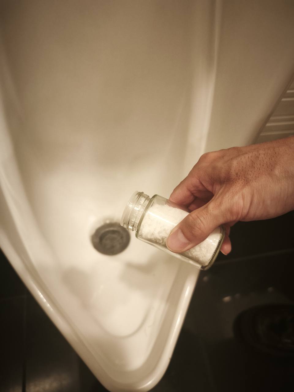 小便器の排水口にさふを散布する様子